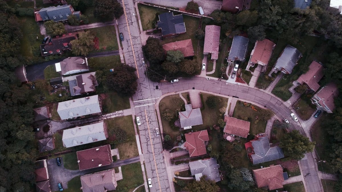 Drone shot capturing suburban neighborhood streets and houses from above.