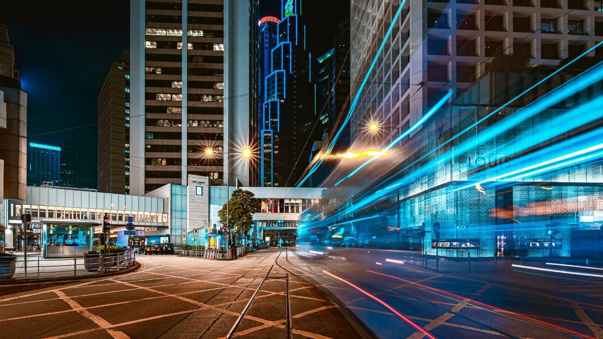 Dynamic urban scene capturing vibrant light trails against a modern city skyline at night.