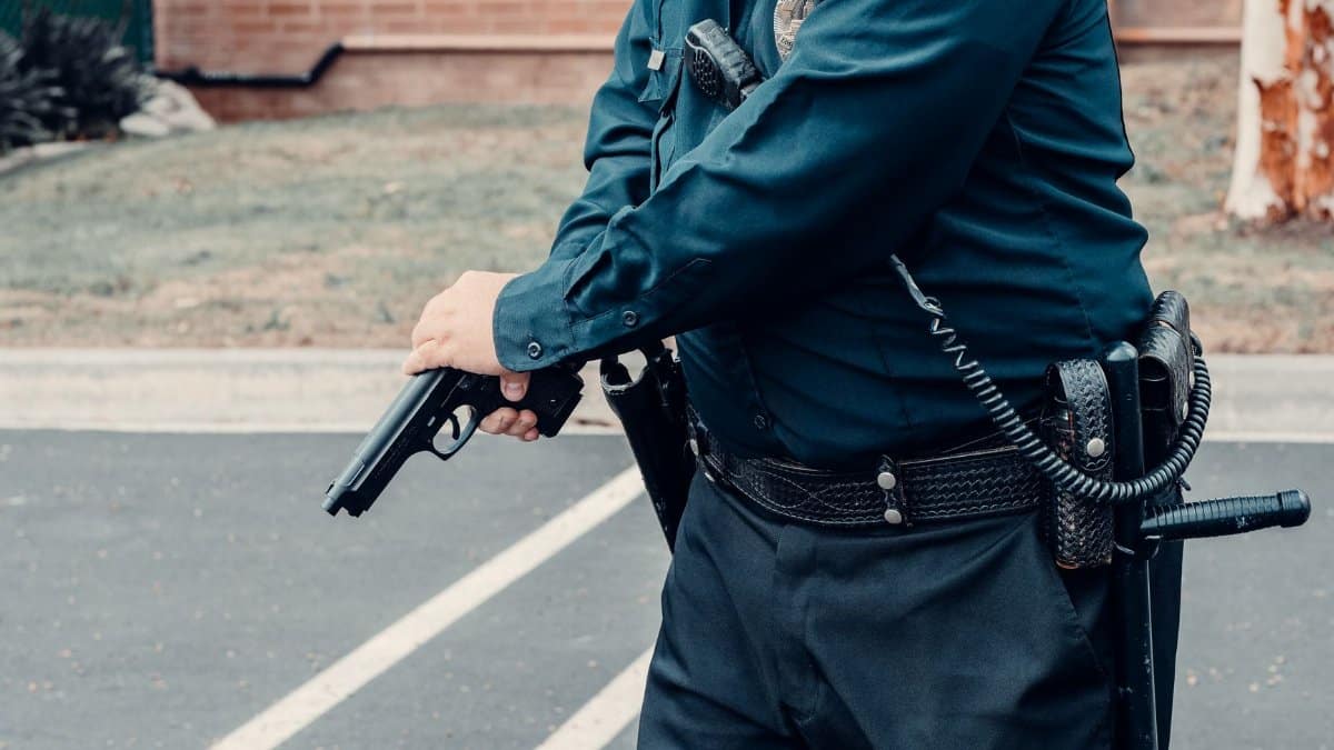 A police officer adjusting a firearm outdoors in a tactical situation, ensuring safety.