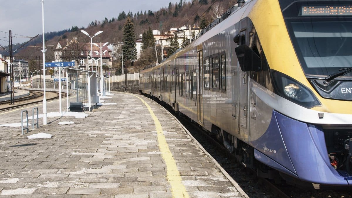 A sleek train waits at the platform of Krynica-Zdrój station in Poland, showcasing modern transportation.