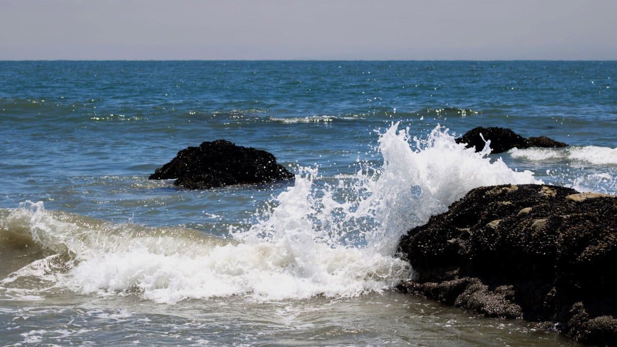 Photograph of powerful ocean waves crashing against rocky formations in Carpinteria, California.