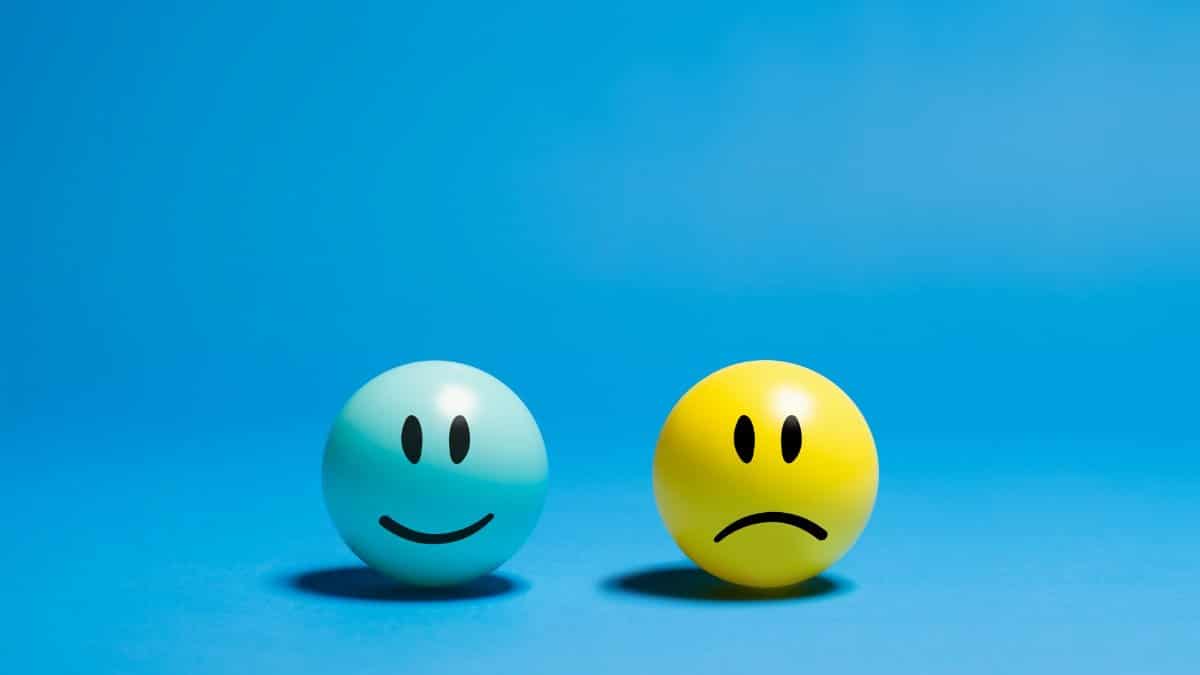Two smiley balls representing opposite emotions on a blue background.