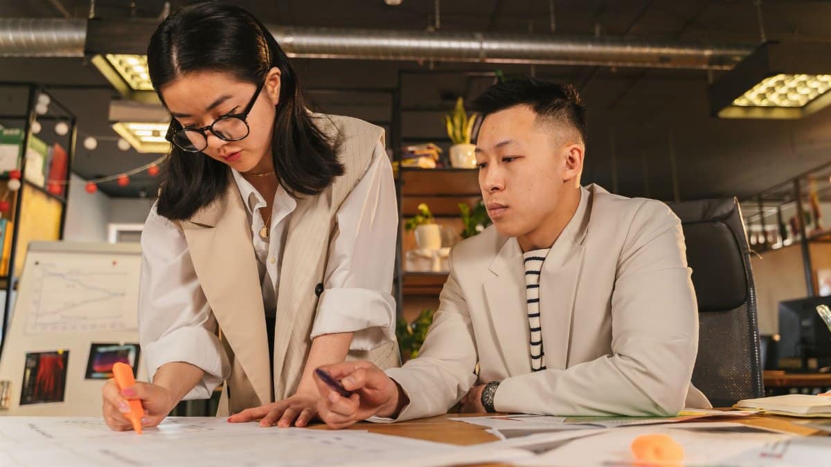 Two coworkers collaborating with documents in a stylish office environment.