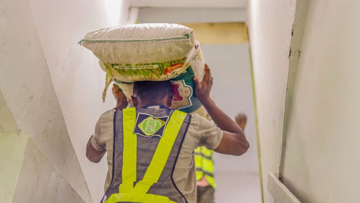 Man carrying a heavy sack up the stairs in a work environment, highlighting labor and effort.