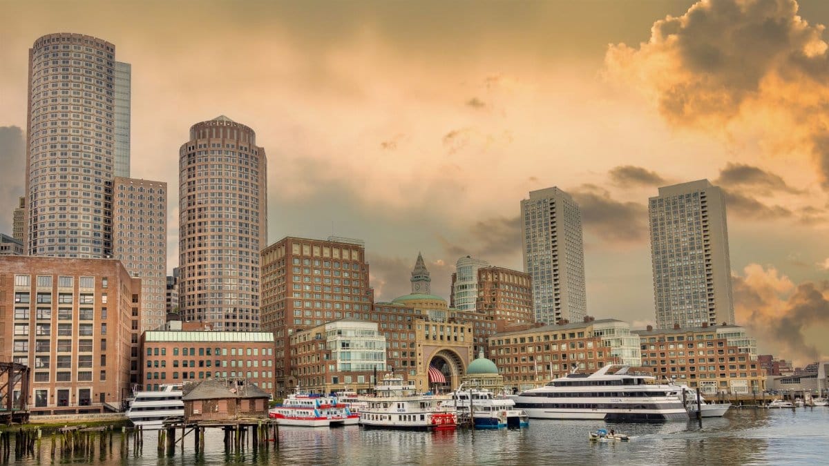 Elegant view of Boston Harbor with skyscrapers and boats at sunset, capturing urban charm.