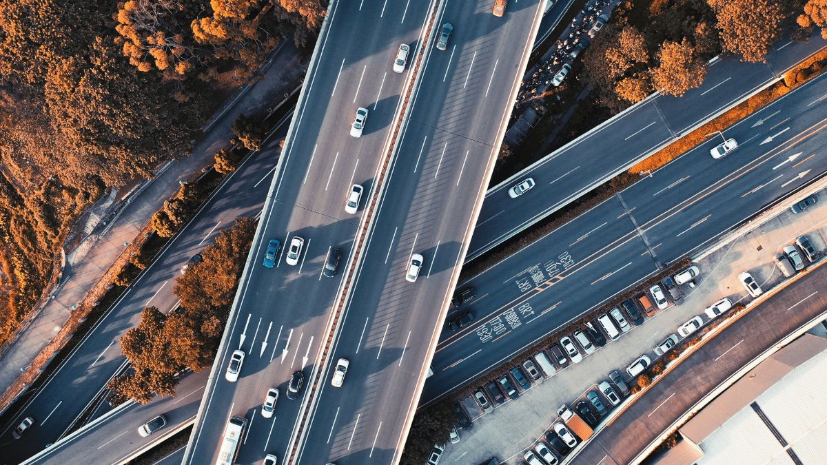 High-altitude view of a highway intersection with moving vehicles and surrounding greenery.