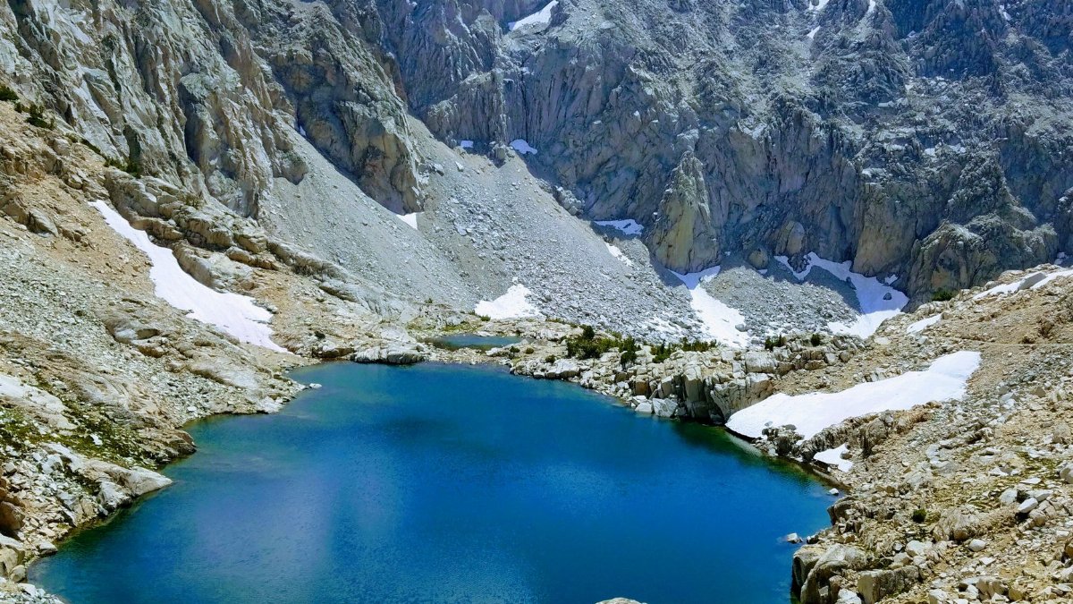 A stunning view of a turquoise alpine lake surrounded by the rugged Sierra Nevada mountains.