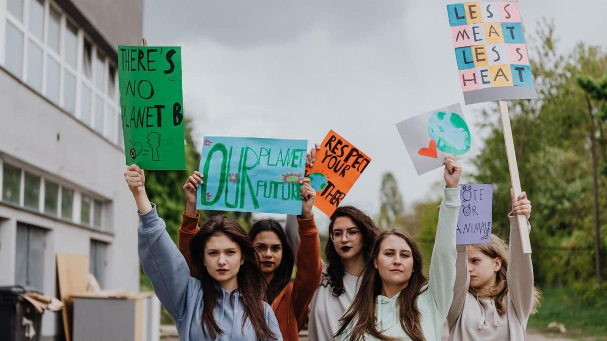 Group of young women holding placards at an outdoor environmental protest.