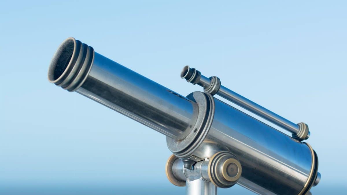 A sleek metallic coin-operated telescope pointing into a clear blue sky, perfect day for sightseeing.