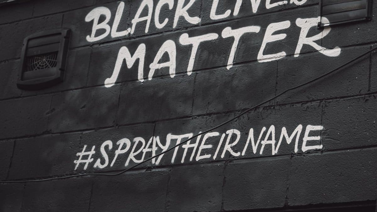 Street art displaying Black Lives Matter slogan and hashtag Spray Their Name, emphasizing social justice.