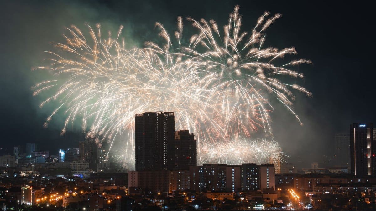 Dazzling fireworks light up the evening sky above an urban skyline, creating a festive atmosphere.