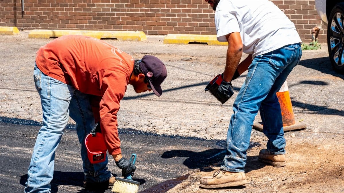 Two workers engaged in asphalt repair on a sunny day in Amarillo, Texas.