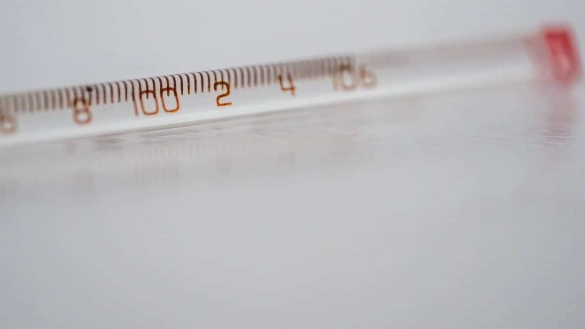 Detailed close-up of a mercury glass thermometer on a white surface, showing temperature measurements.