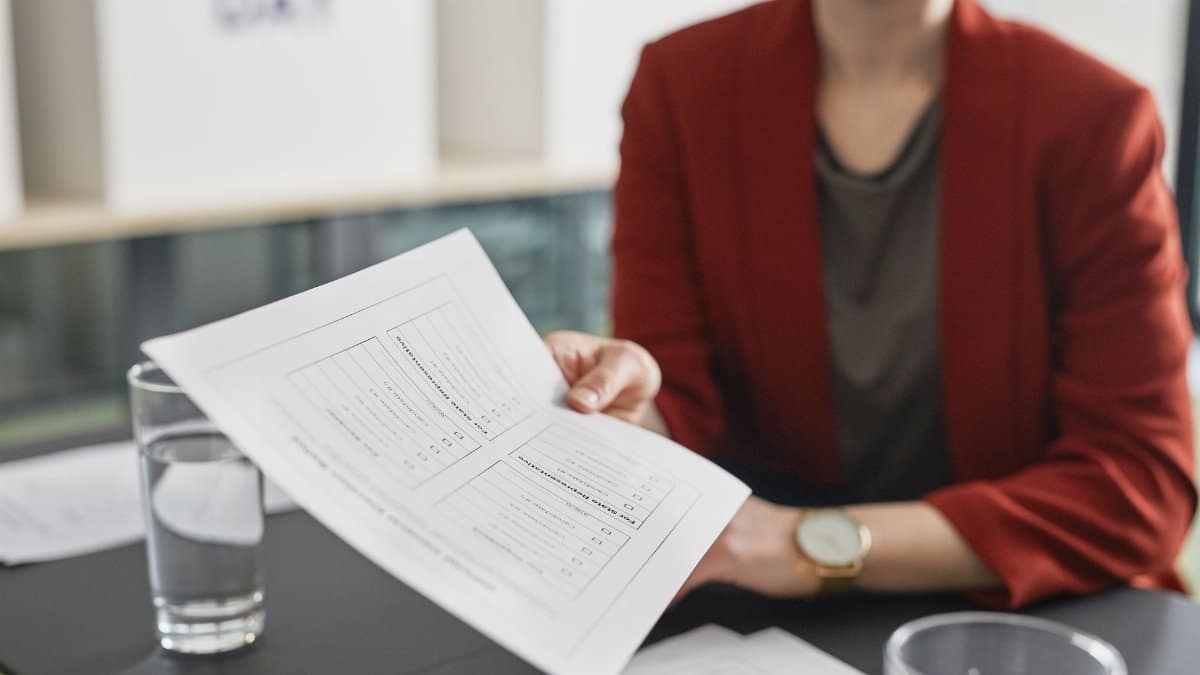 Close-up of a person handing over a business document during a meeting.
