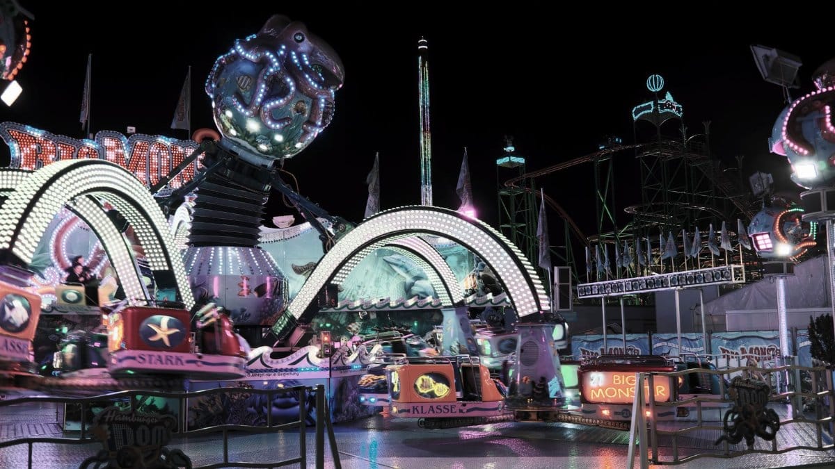 Colorful amusement park rides illuminated at night in Hamburg, showcasing lively attractions.