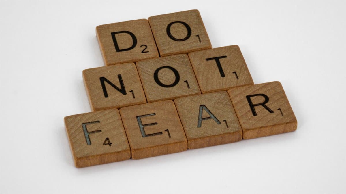 Wooden Scrabble tiles arranged to spell 'DO NOT FEAR' on a white background.