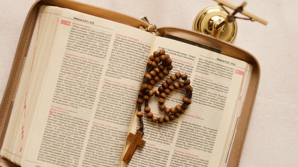 An open Bible in Polish with rosary beads and crucifix, symbolizing faith and prayer.