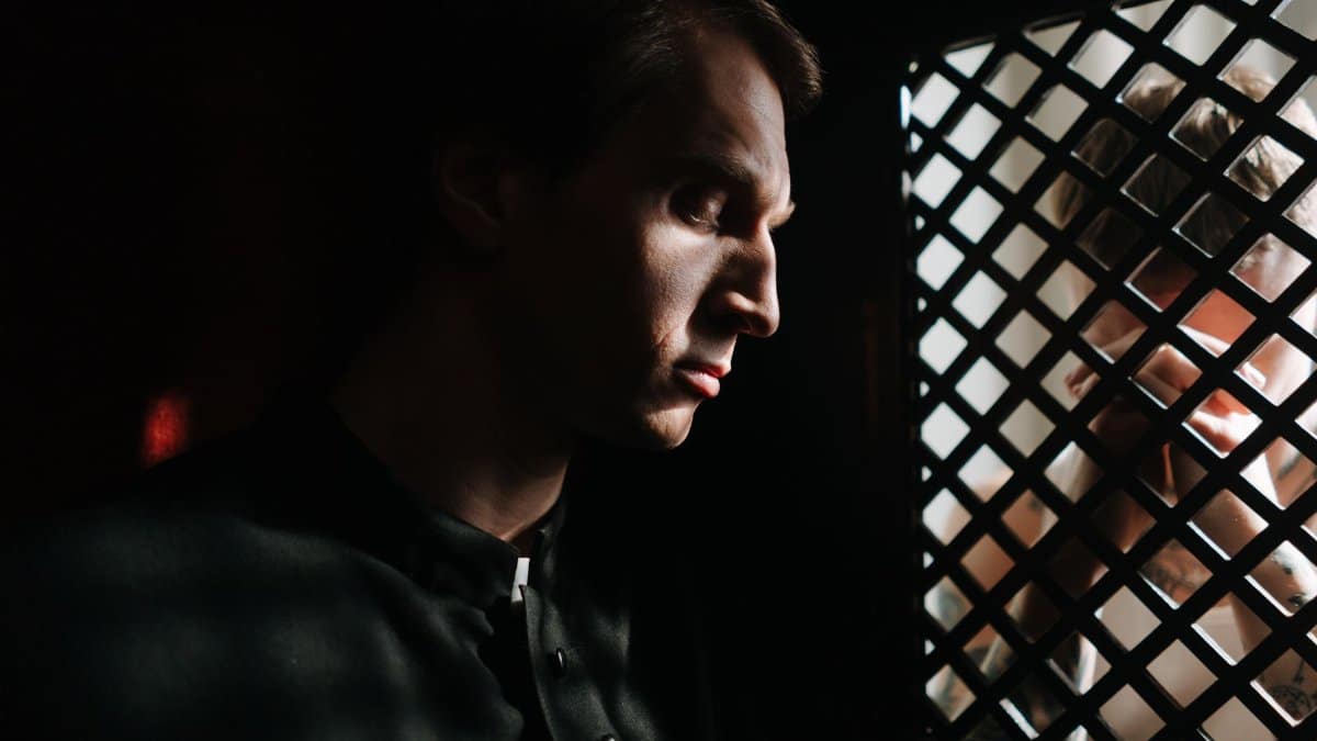 A contemplative priest listens to a confession in a dimly lit church setting, capturing a moment of faith and spirituality.