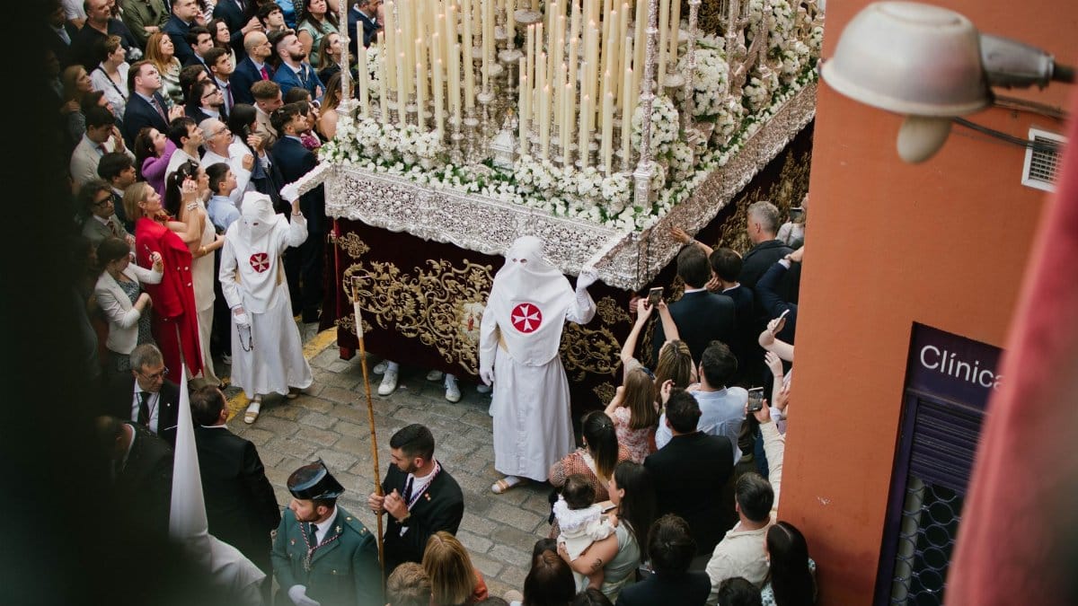 A colorful Holy Week procession with traditional attire in Seville, Spain.