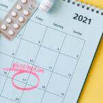 Calendar with vaccination date circled alongside vaccine vials and syringe for COVID-19 prevention.