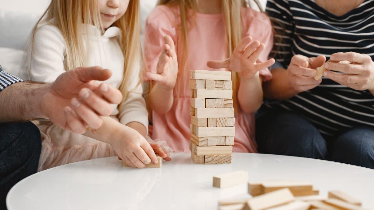 A family playing Jenga indoors creates a bonding experience and fun moment together.
