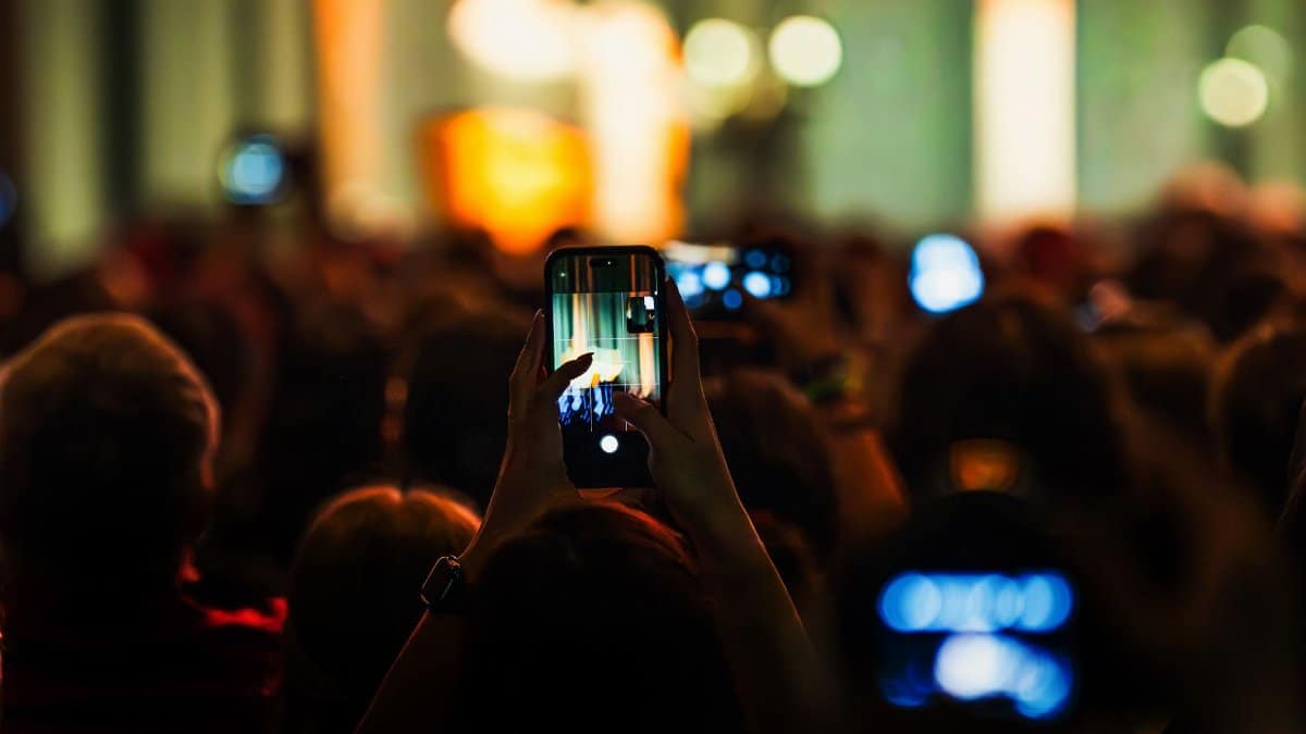 Audience recording live concert with smartphones, vibrant and energetic atmosphere.