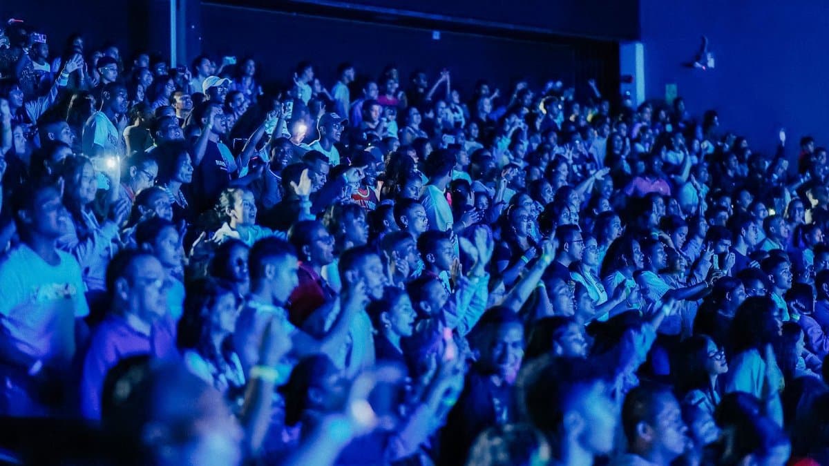 A packed crowd enjoys a live concert, bathed in dynamic blue lighting, capturing excitement.