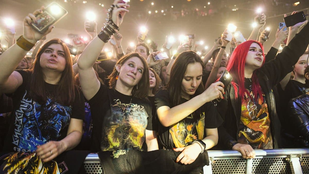 Fans enjoying a live rock concert, capturing moments with cell phones.