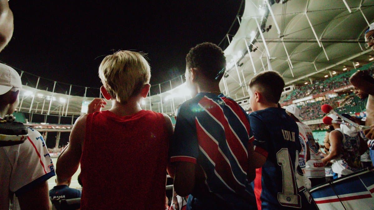 Fans cheer from the stands during a night soccer game in a large stadium, full of energy and excitement.