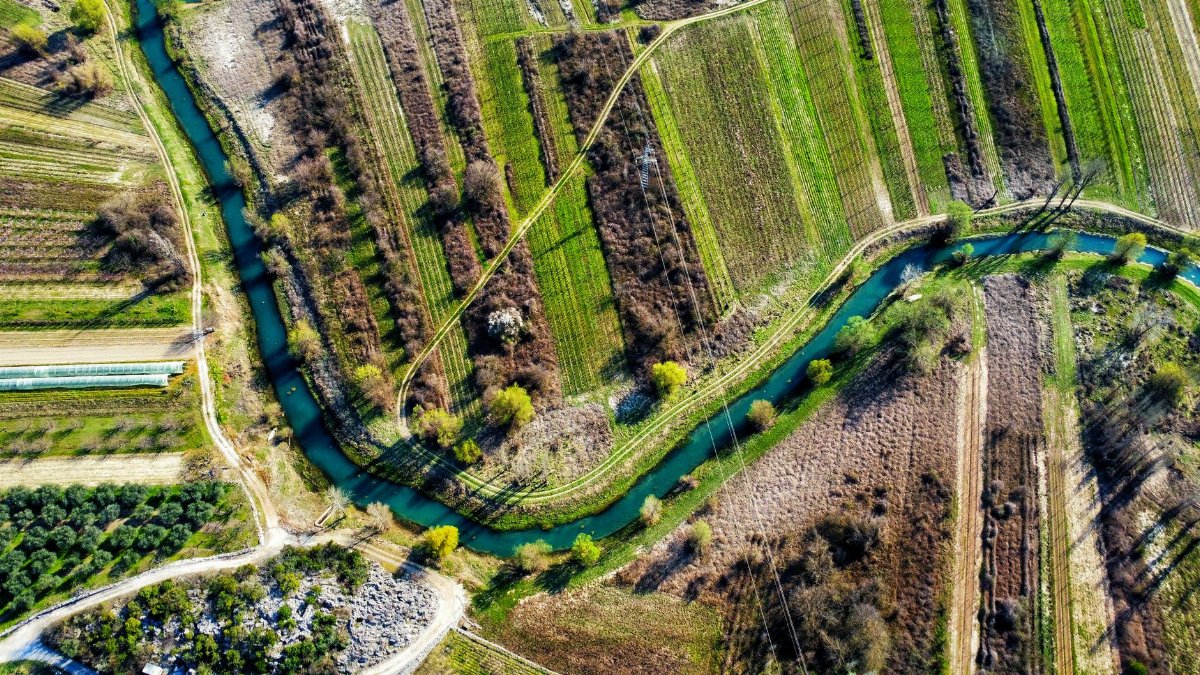 Aerial view of lush agricultural fields and winding river in Vrgorac, Croatia.