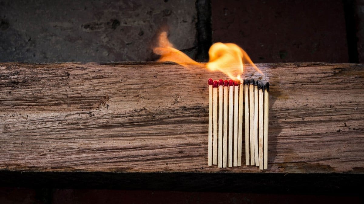 Burning matches on wooden beam symbolize chain reaction and potential hazard.