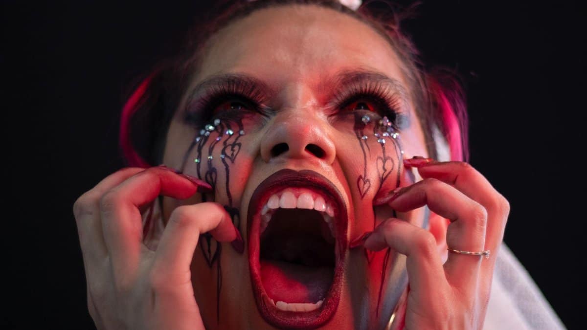 A woman with artistic makeup screams in terror, evoking a sense of fear.