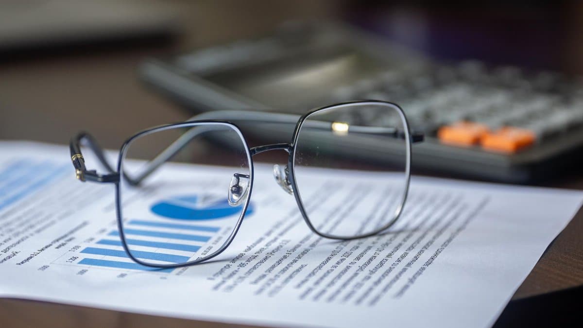 Eyeglasses on financial report with calculator in office setting, highlighting analysis.