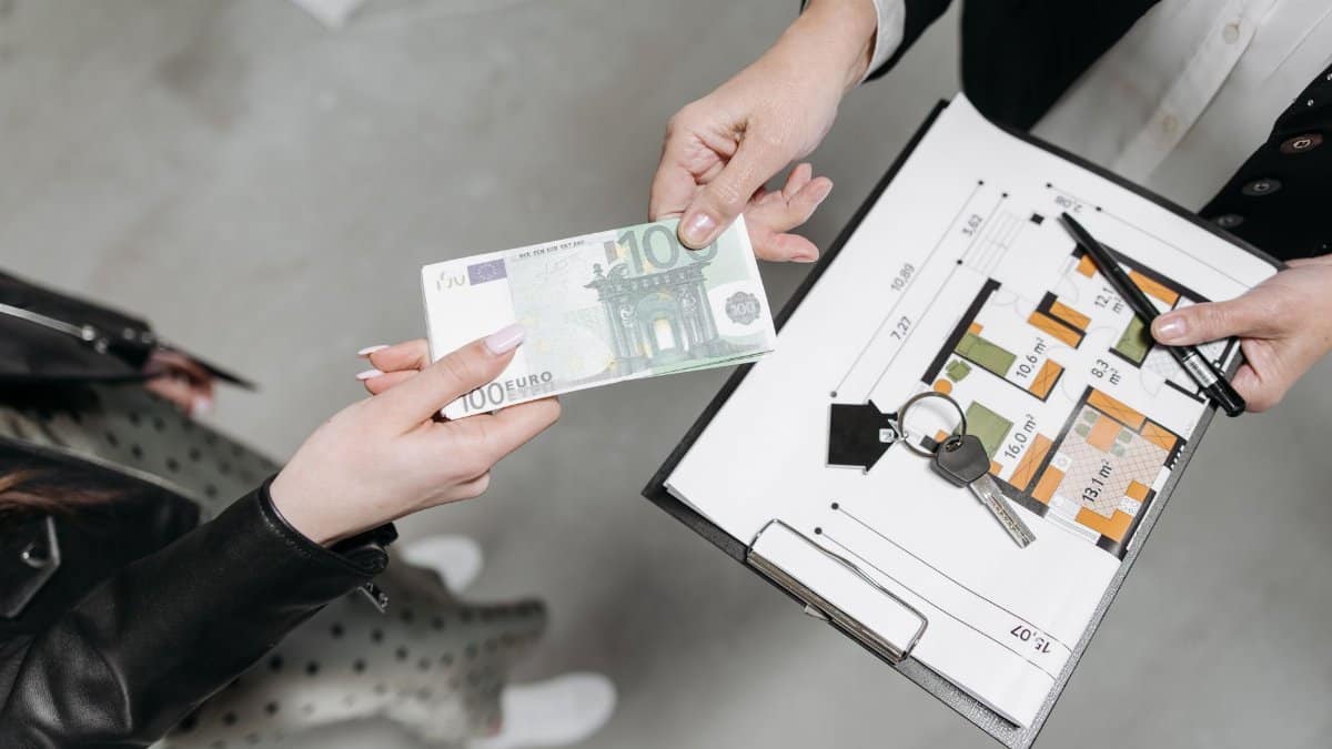 Close-up of a real estate transaction with euro bill, keys, and floor plan.