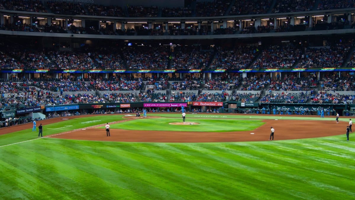 An engaging baseball game with a full crowd at Texas stadium under bright lights.