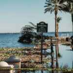 A flooded pathway with caution tape and palm trees by a lake in Sanford, Florida.