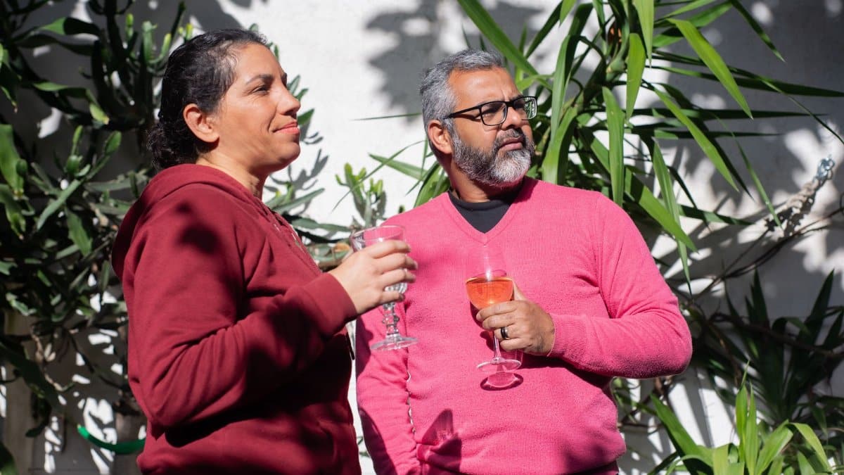 Middle-aged couple sipping wine outdoors in Portugal, surrounded by greenery.