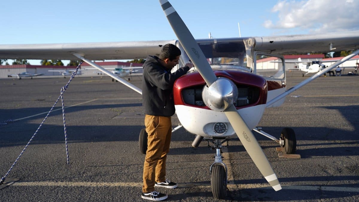 A man inspecting a small airplane at Hayward airfield on a clear day, perfect for aviation enthusiasts.