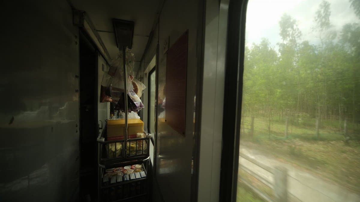A food cart inside a train with a view of green countryside passing by.