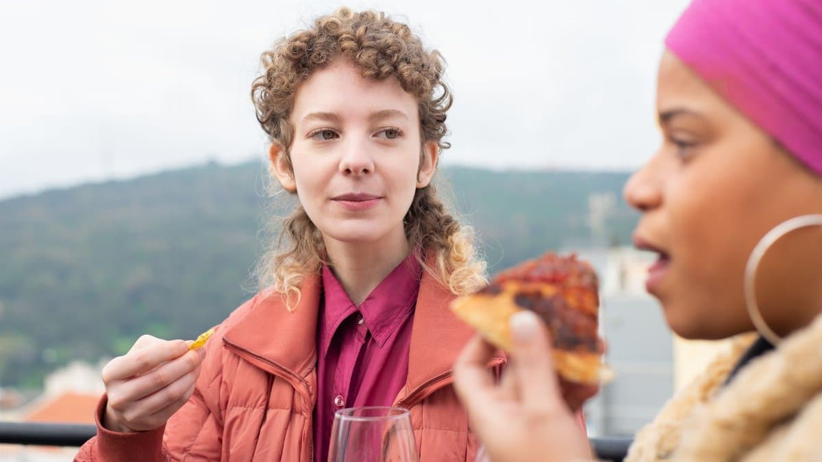 Two friends enjoying food outdoors with scenic mountain views in Portugal.