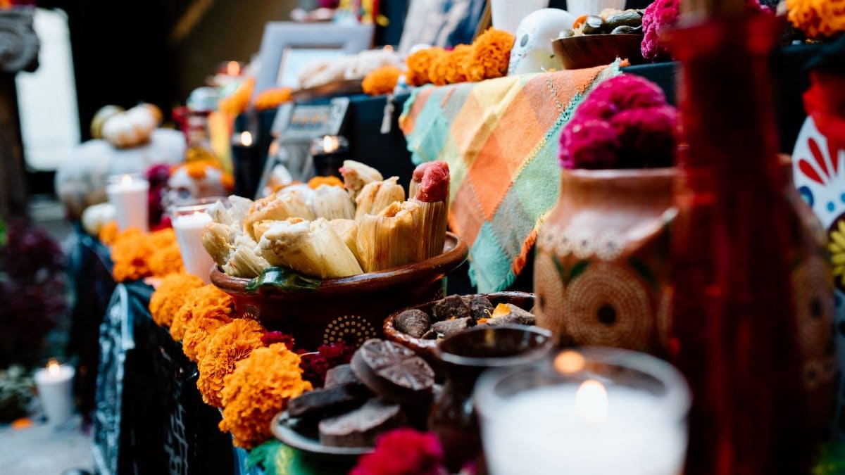 Colorful Day of the Dead altar with traditional offerings including tamales and candles in Guadalajara, Mexico.