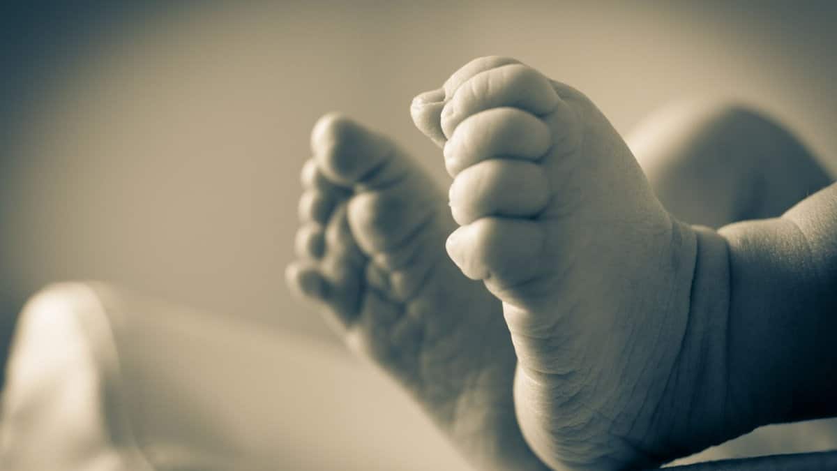 Close-up of newborn baby feet in a soft-focus, monochrome setting, symbolizing innocence and new beginnings.