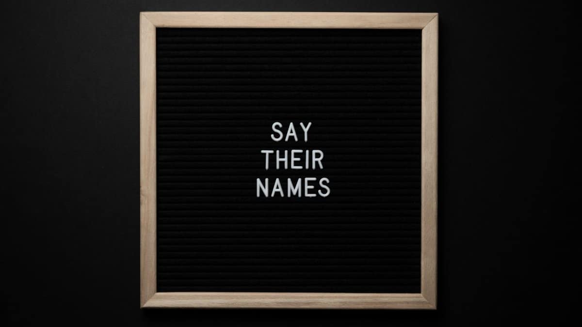 Top view composition of black framed photo with white text Say Their Names placed on black background