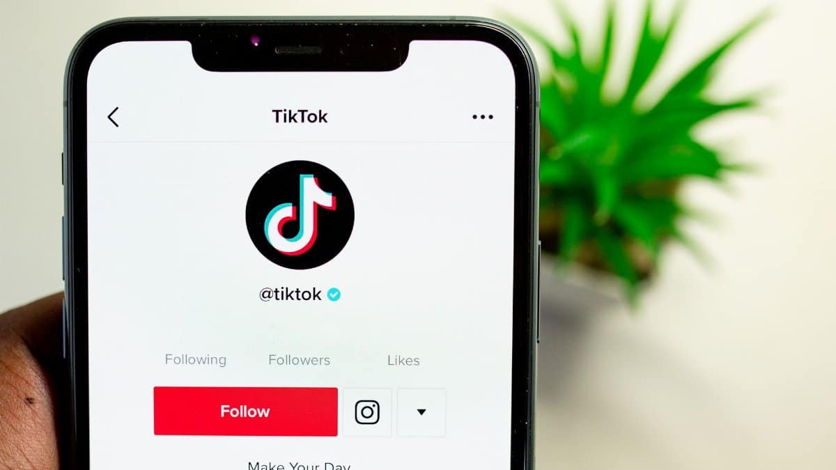 Close-up view of hand holding smartphone displaying TikTok app interface with profile page.