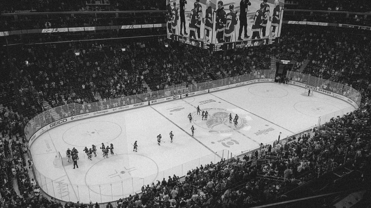Black and white overhead shot of a thrilling ice hockey game with a full audience in an indoor arena.