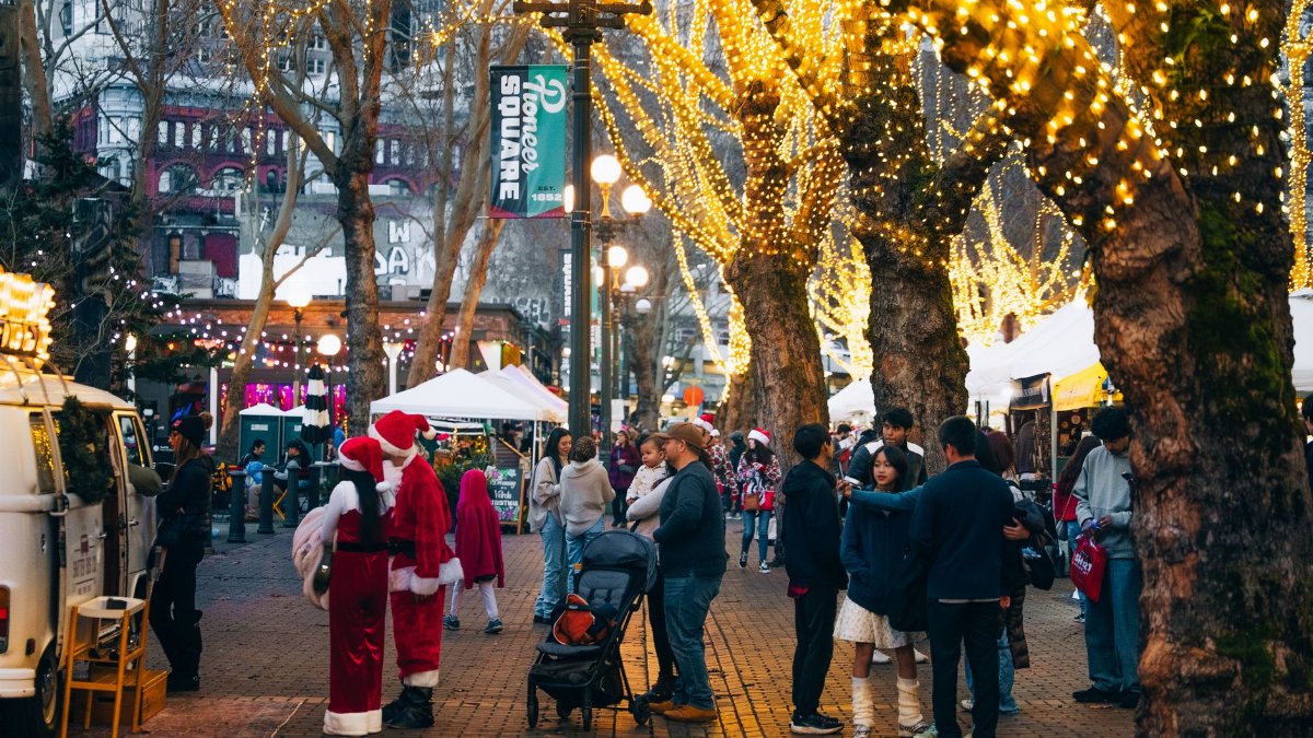 Vibrant holiday scene at Pioneer Square with festive lights and people enjoying the winter market.