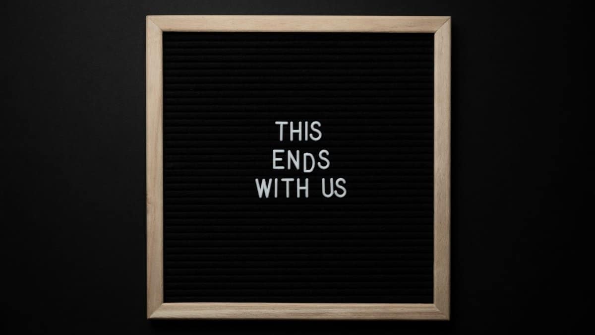 From above wooden frame with dark background with quote THIS ENDS WITH US on center on black background