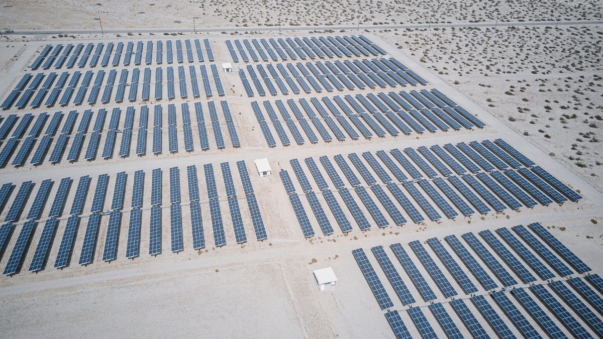 Expansive aerial view of solar panels in a desert, showcasing renewable energy technology.