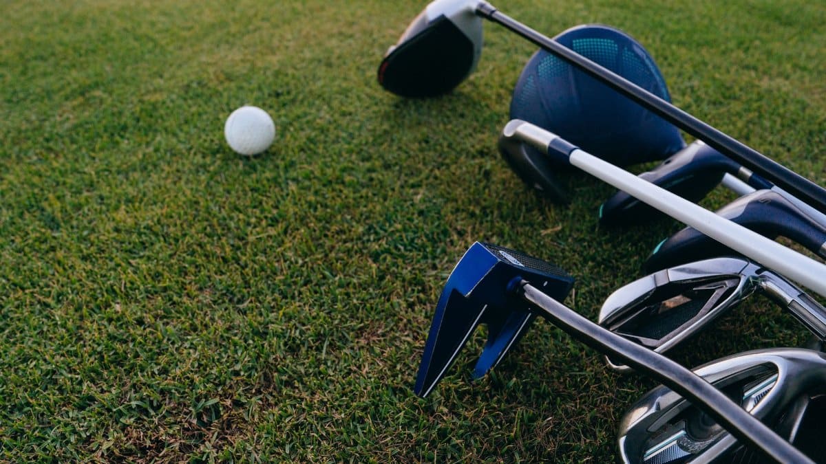 A close-up view of golf clubs and a golf ball on a lush green grass field.