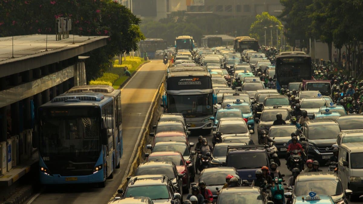 Heavy traffic in a city with cars, buses, and motorcycles on a crowded road.